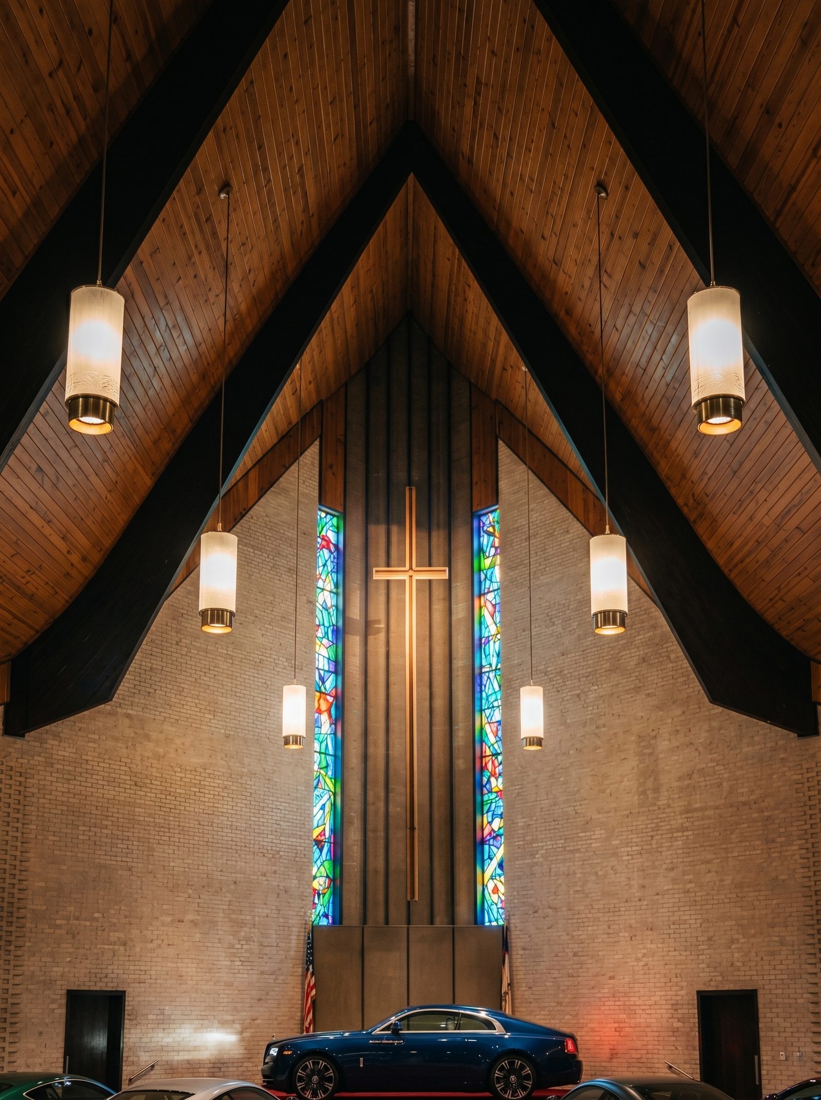 The stained-glass window, wooden cross, and vaulted ceiling of the sanctuary